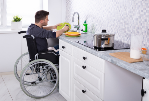 man in a wheelchair washing dishes